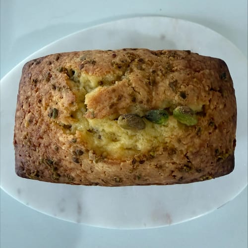 Pistachio Rose Garden mini loaf cake with pistachios baked on top, served on a white plate for the Base & Bloom Garden Party collection.