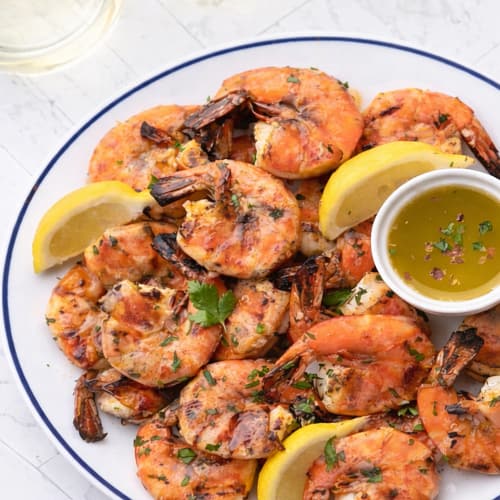 Lemon Garlic Roasted Shrimp Scampi plated with roasted shrimp, lemon wedges, and fresh herbs.