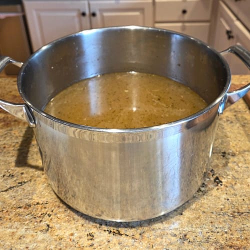 Homemade chicken stock in a large pot, prepared from roasted chicken for the May 26 Taste the Trend class.