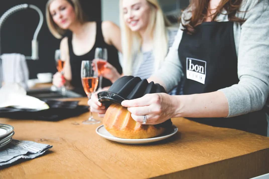 Hands removing a bundt cake from a baking mold during a home cooking essentials class at bon COOK