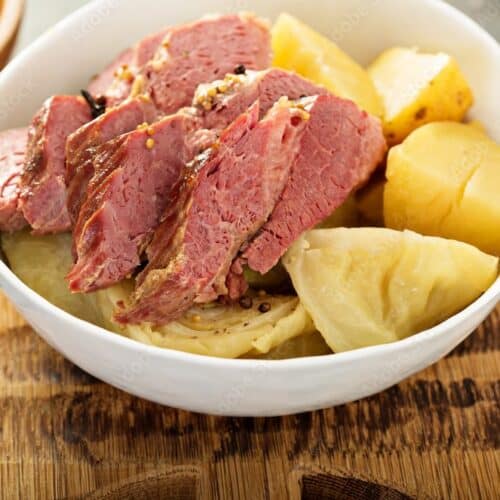 Corned beef and cabbage served with potatoes in a white bowl