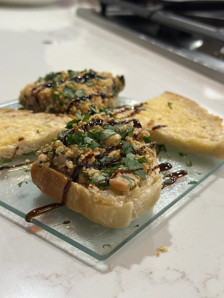 Leek and Butter Bean Bake served on toasted bread, garnished with herbs and balsamic drizzle